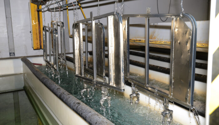 A set of zinc-plated steel gates for an abbatoir receive their final rinse in the electroplating process.